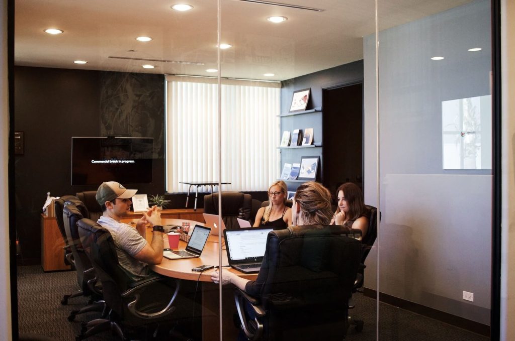Small team meeting inside a glass-walled conference room discussing project strategy